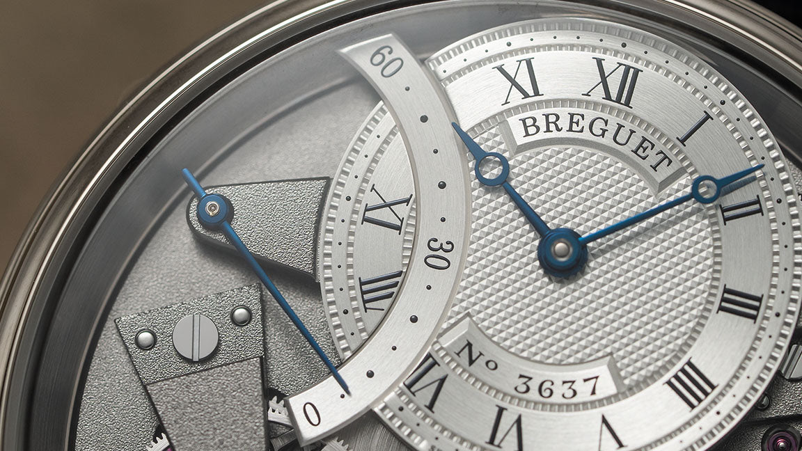 Macro close up of a Breguet wristwatch dial with Roman numerals and blue hands