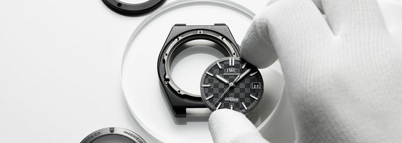 Close up of an IWC Ingenieur wristwatch held by gloved hands during assembly.