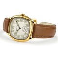 Close-up of gold-tone cushion watch with white dial and large luminous Arabic numerals on a brown leather strap.