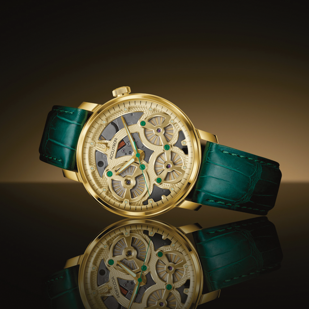 Spaceview Evolution champagne gold skeleton watch on green leather strap against a dark gradient background with reflection.