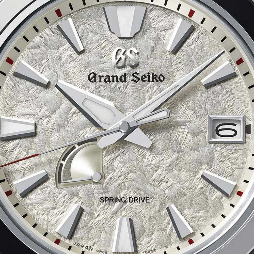 Close up of Grand Seiko ivory textured dial with logo and bold applied hour markers.