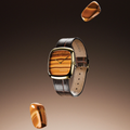 Dennison tiger eye dial watch with gold case and dark brown leather strap against brown background