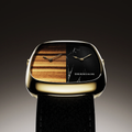 Close up of the gold toned ALD Dual Time dial split into tiger eye left and marble right with a leather strap