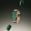 Floating view of a gold case watch with green malachite dial on a green leather strap