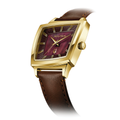 Gold-toned cushion-shaped watch with burgundy dial and brown leather strap