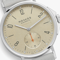 Close-up of Ahoi Neomatik Sand beige dial with silver hands and orange subdial hand on a beige fabric strap