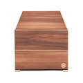 Four watch winder in warm wood finish with gold feet and a small logo badge on the front