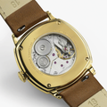 Gold-tone cushion watch back with brown leather strap showing exposed movement
