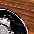 Close up of a stainless steel watch partially visible inside a wood finished watch winder