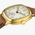 Angled close-up of gold-tone cushion watch with brown leather strap and crown detail.