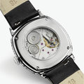 Case back view of the watch showing the exposed movement with gears and purple jewels