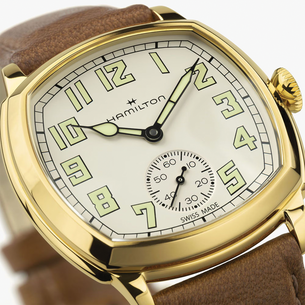 Close-up of a gold-tone cushion watch with beige leather strap and Hamilton branding