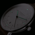 Hamburg watch dial in low light with glowing teal luminescent hands and markers